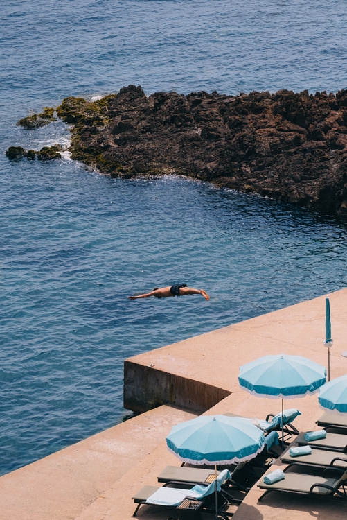 Homme plongeant dans l'eau transparente depuis le ponton de la plage privée du Tiara Miramar Beach Resort.