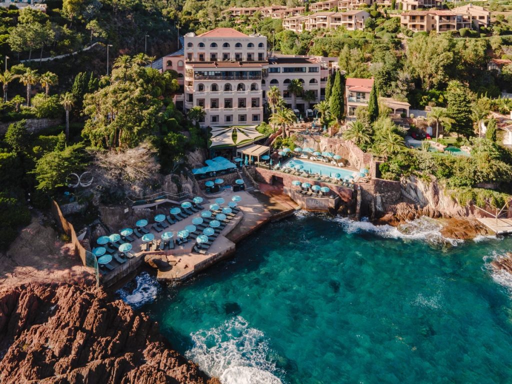 Vue aérienne de l'hôtel 5 étoiles Tiara Miramar Beach Resort & Spa, sa piscine, sa plage privée et ses falaises rouges à Théoule-sur-Mer près de Cannes.
